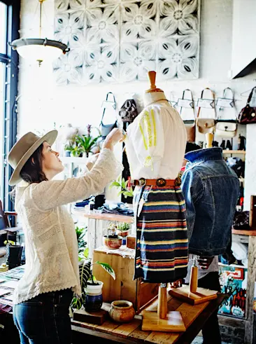 Mujer colocando ropa en la vitrina de una tienda.