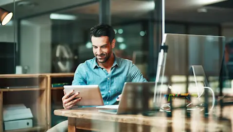 Man looking at tablet from desktop workstation