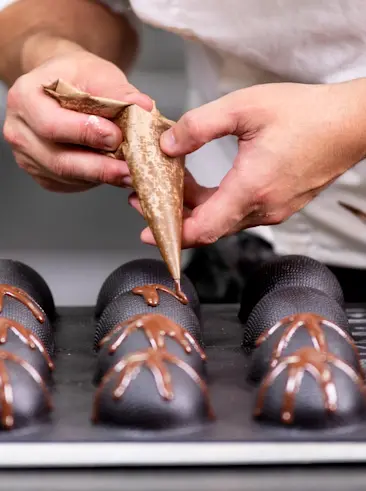 Bäcker beim Dekorieren von Schokoladenbonbons.