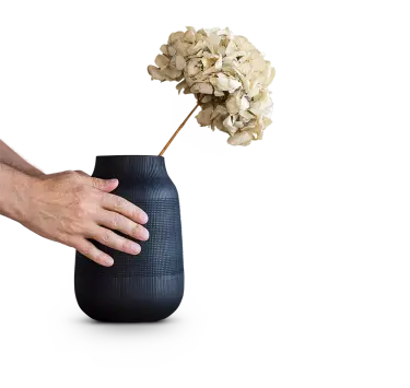 Hände auf Vase mit getrockneter Blume