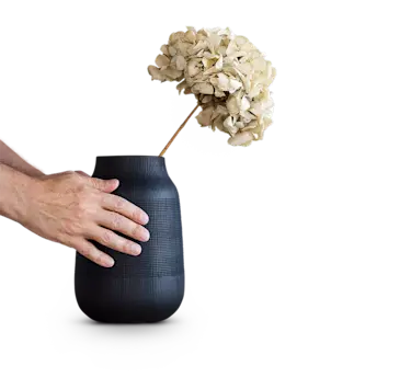 Hände auf Vase mit getrockneter Blume