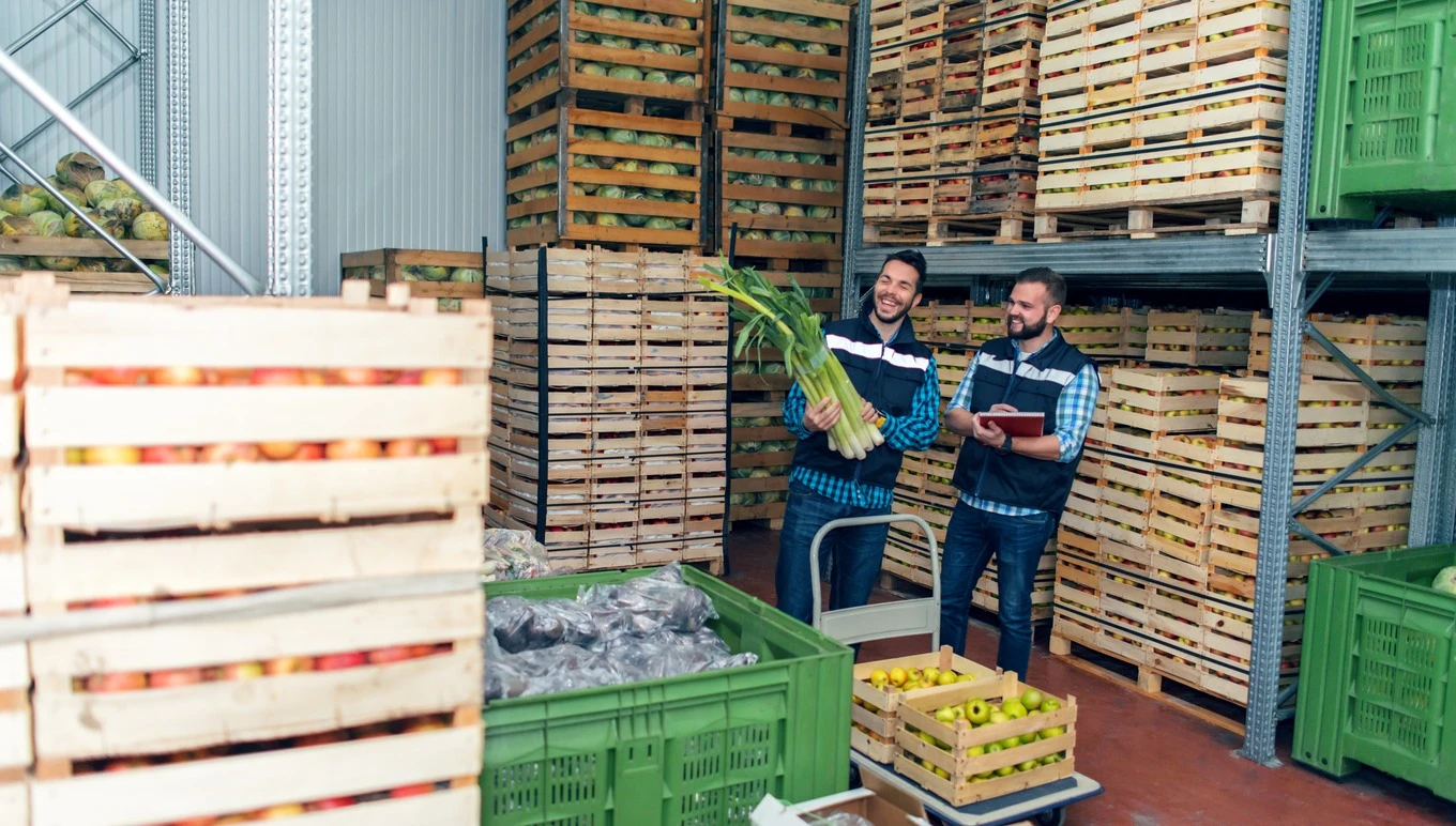 Food facility workers handle inventory in warehouse.