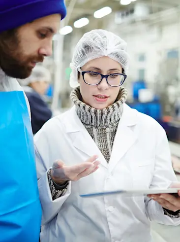 Twee personen voeren een gesprek in een fabriek.