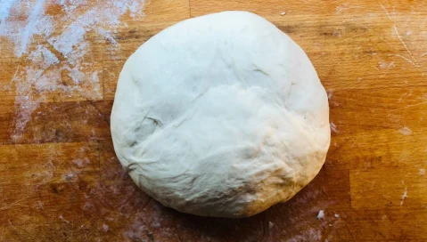 A ball of pizza dough on wood table
