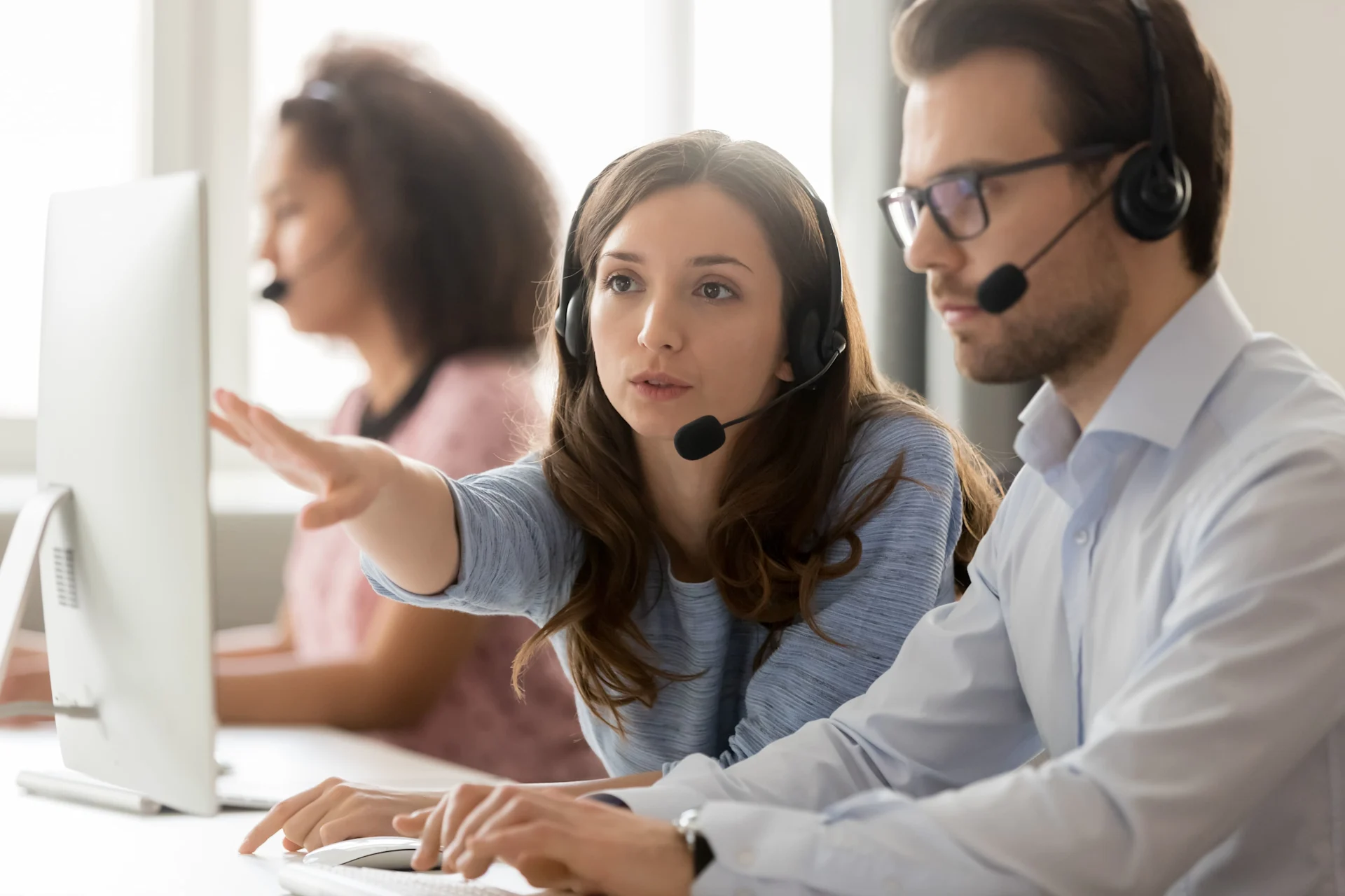 Call centre worker helping a new employee at a customer support desk