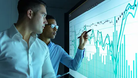 Business professionals scrutinize a graph of rising costs.