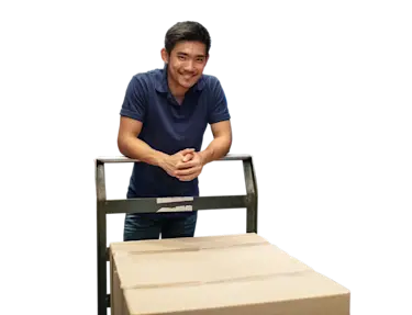 Man smiling with a warehouse cart carrying a box.