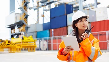 Cargo loading dock worker on radio and looking at tablet