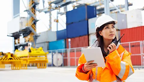 Cargo loading dock worker on radio and looking at tablet