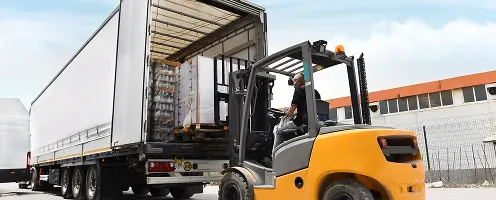A forklift loading pallets onto a truck.