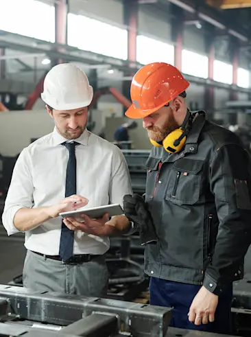 Twee arbeiders kijken naar een tablet.