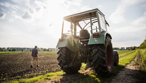A farmer tends to his crops after parking his tractor.