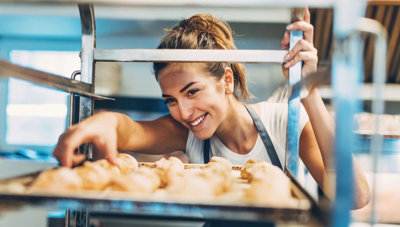 A bakery worker checks on croissants.