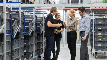 Four people conversing next to stacked plastic crates