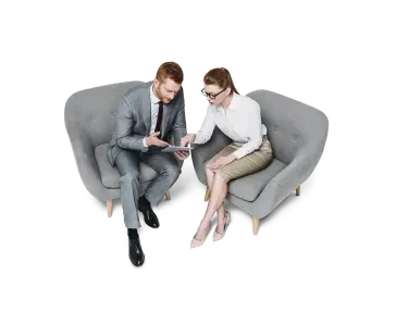 Man and woman talking over tablet from sofa chairs