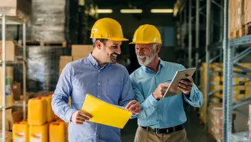 Business men walking warehouse hardhats