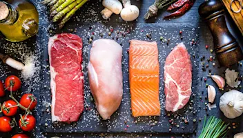 Cuts of beef, chicken, salmon and pork on cutting board