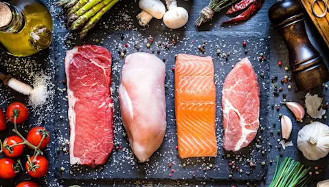 Cuts of beef, chicken, salmon and pork on cutting board