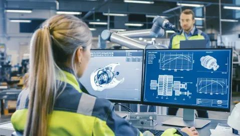 Engineer at car factory looking at car parts on computer screen.