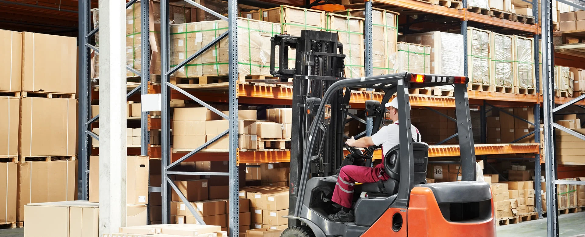 Forklift driver moving goods inside an industrial warehouse