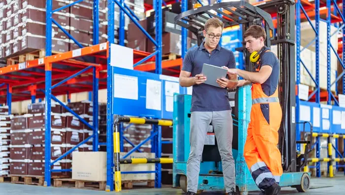 Two men with a tablet standing in a warehouse.