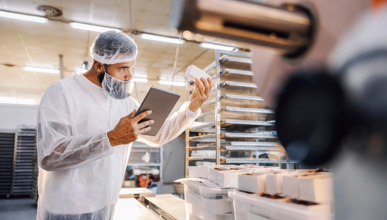 A food manufacturing professional uses software on a tablet while inspecting ingredients.