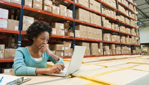 Woman on computer in warehouse