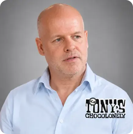 Tony’s Chocolonely logo featuring a person in the background making chocolate bars in a factory