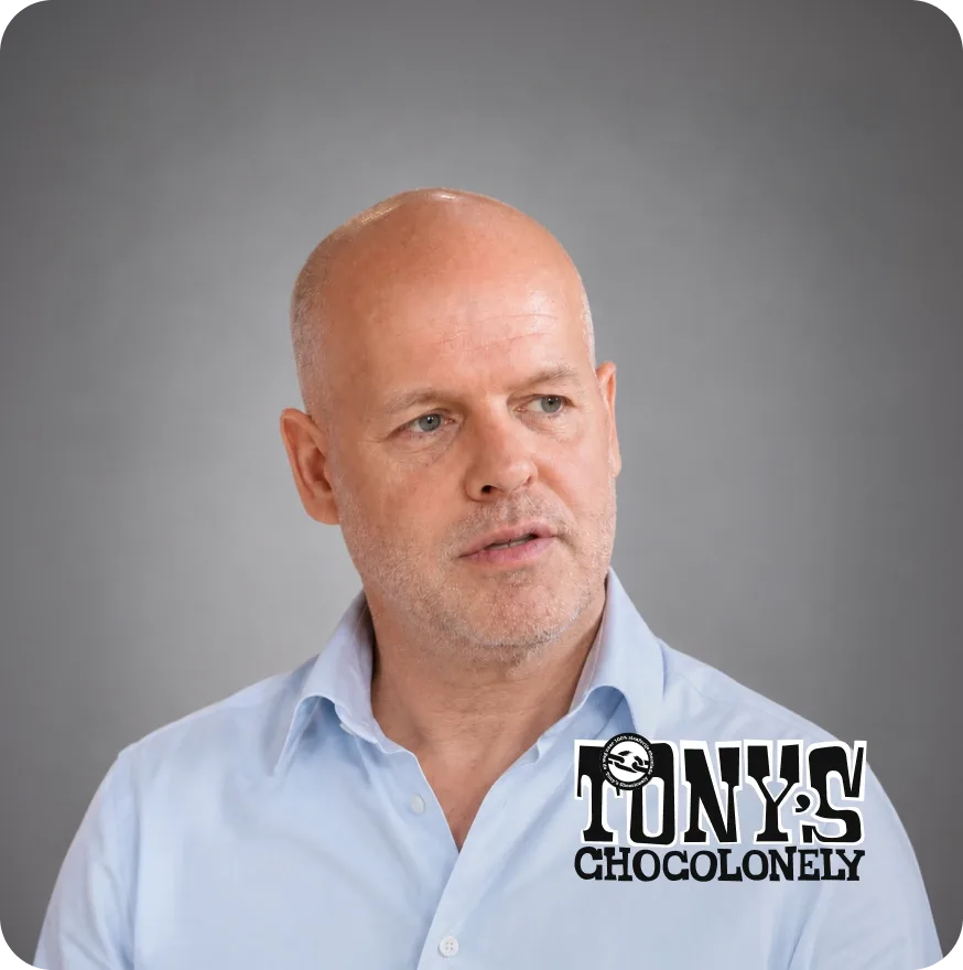 Tony’s Chocolonely logo featuring a person in the background making chocolate bars in a factory
