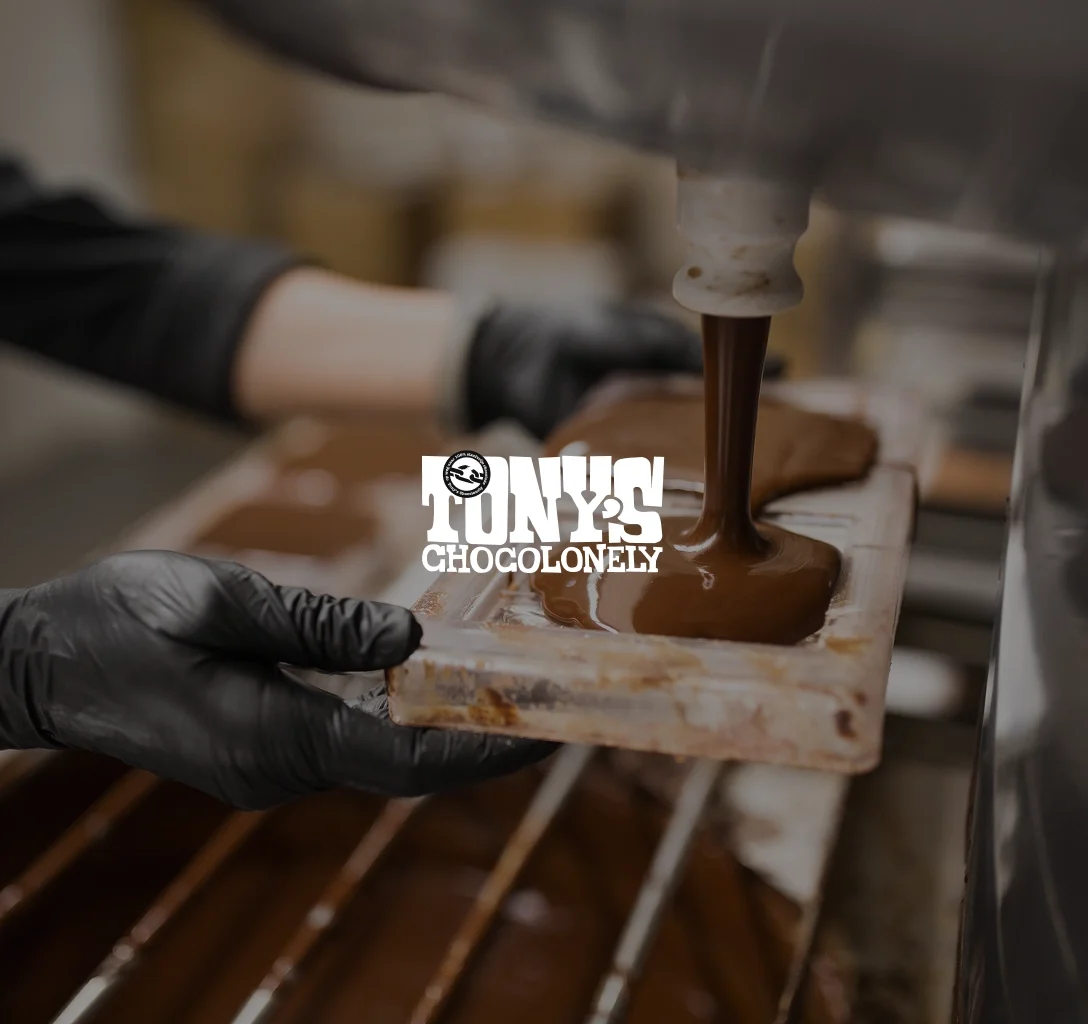Tony’s Chocolonely logo featuring a person in the background making chocolate bars in a factory