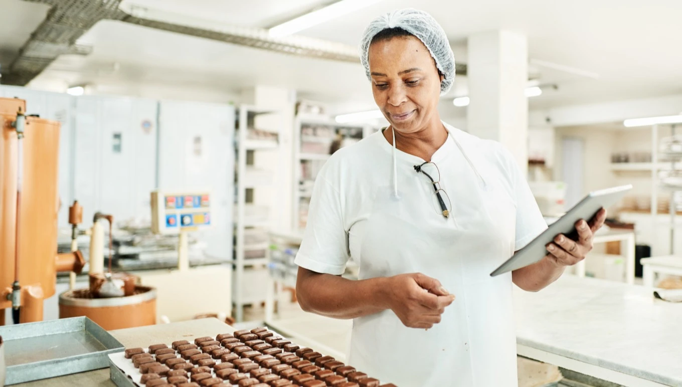 A food facility worker inspects chocolates.