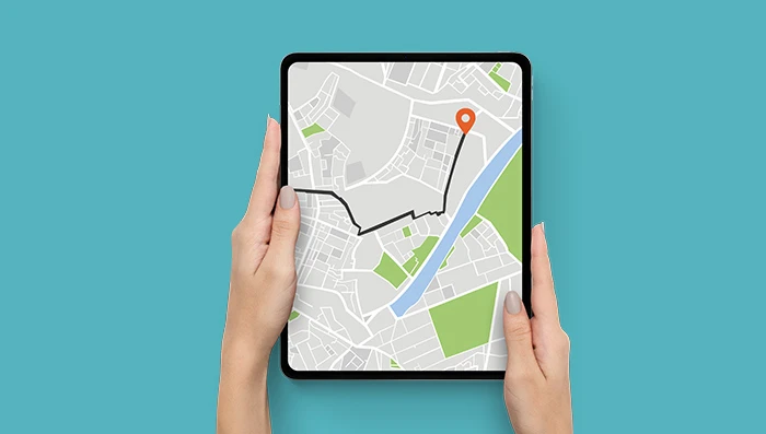 Person holding a tablet while the screen displays navigation.