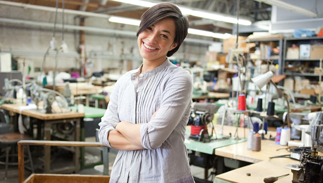 A fashion and apparel professional smiles confidently in the warehouse.