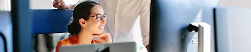 Coworkers looking at computer monitors on desk