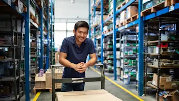 Worker in warehouse moving box with dolly