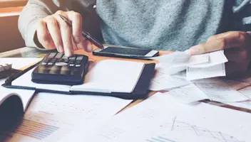 Man working with calculator and has a lot of receipts.