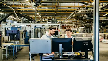 Engineers behind monitor in factory