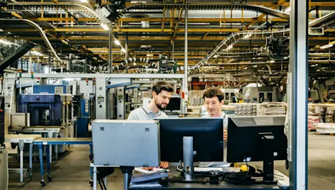 Engineers behind monitor in factory