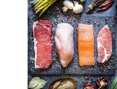 Fleischstücke, Huhn, Lachs und Schweinefleisch auf dem Schneidebrett