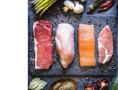 Cortes de carne, pollo, salmón y cerdo sobre tabla de cortar de mesa