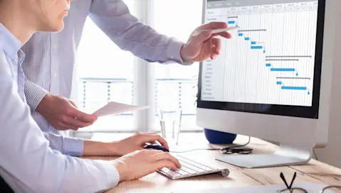 Business professionals consult charts on a computer.
