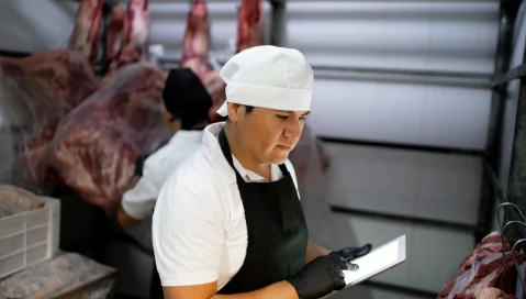 A meat distribution business employee utilizes ERP features via a tablet.