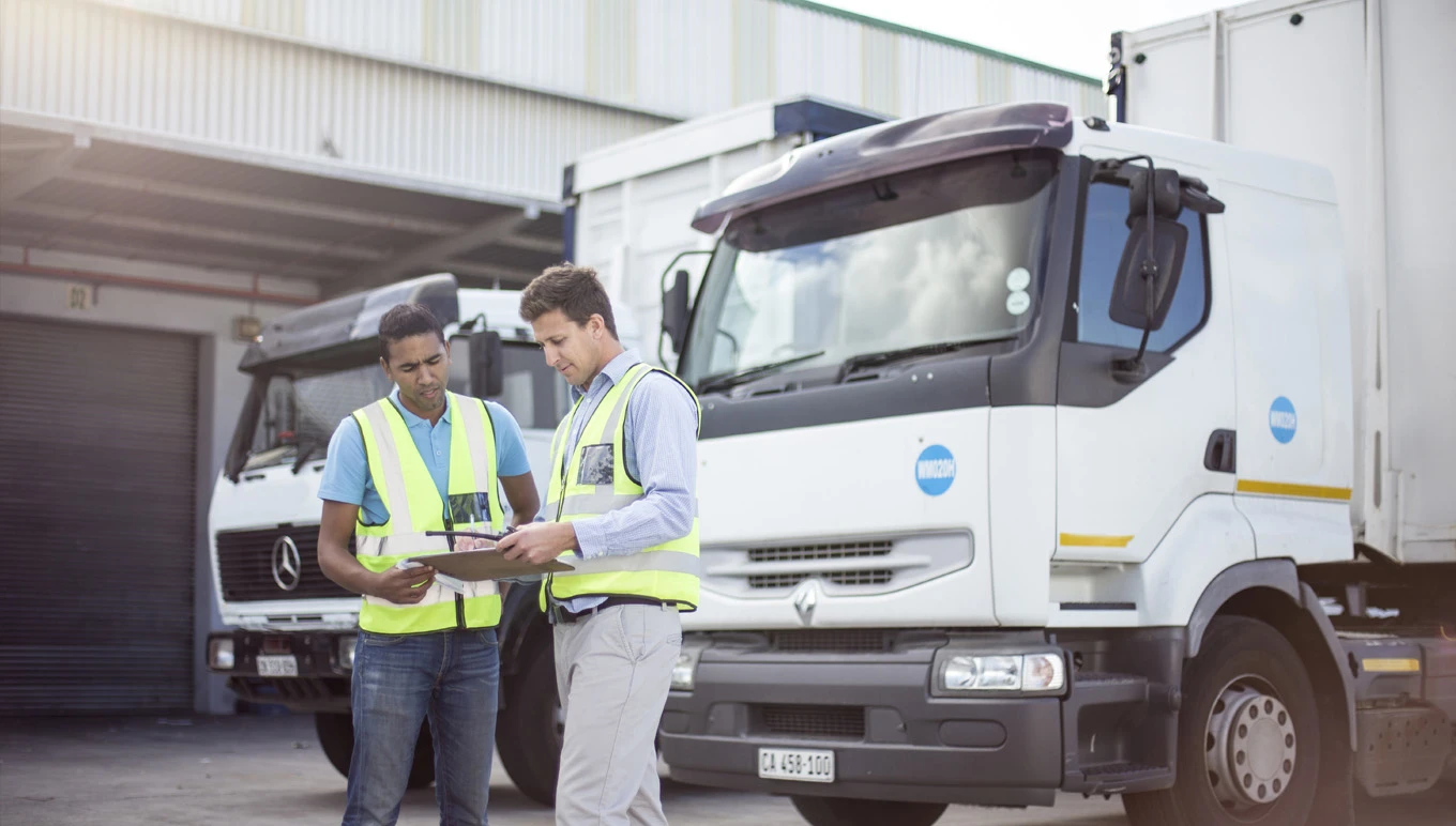 Two delivery drivers reviewing tablet before departure