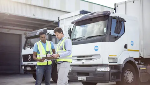 Two delivery drivers reviewing tablet before departure