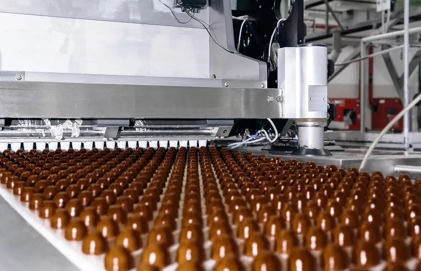 Chocolate toppings on the conveyor of a confectionery factory