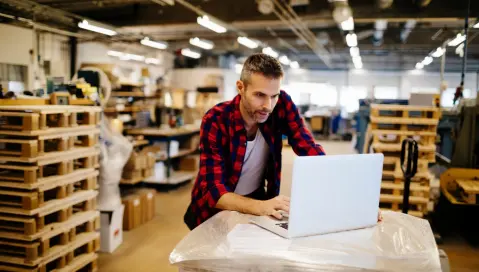 Man using laptop in warehouse