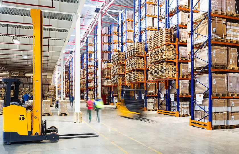 Warehouse with rows of pallets and a forklift truck.