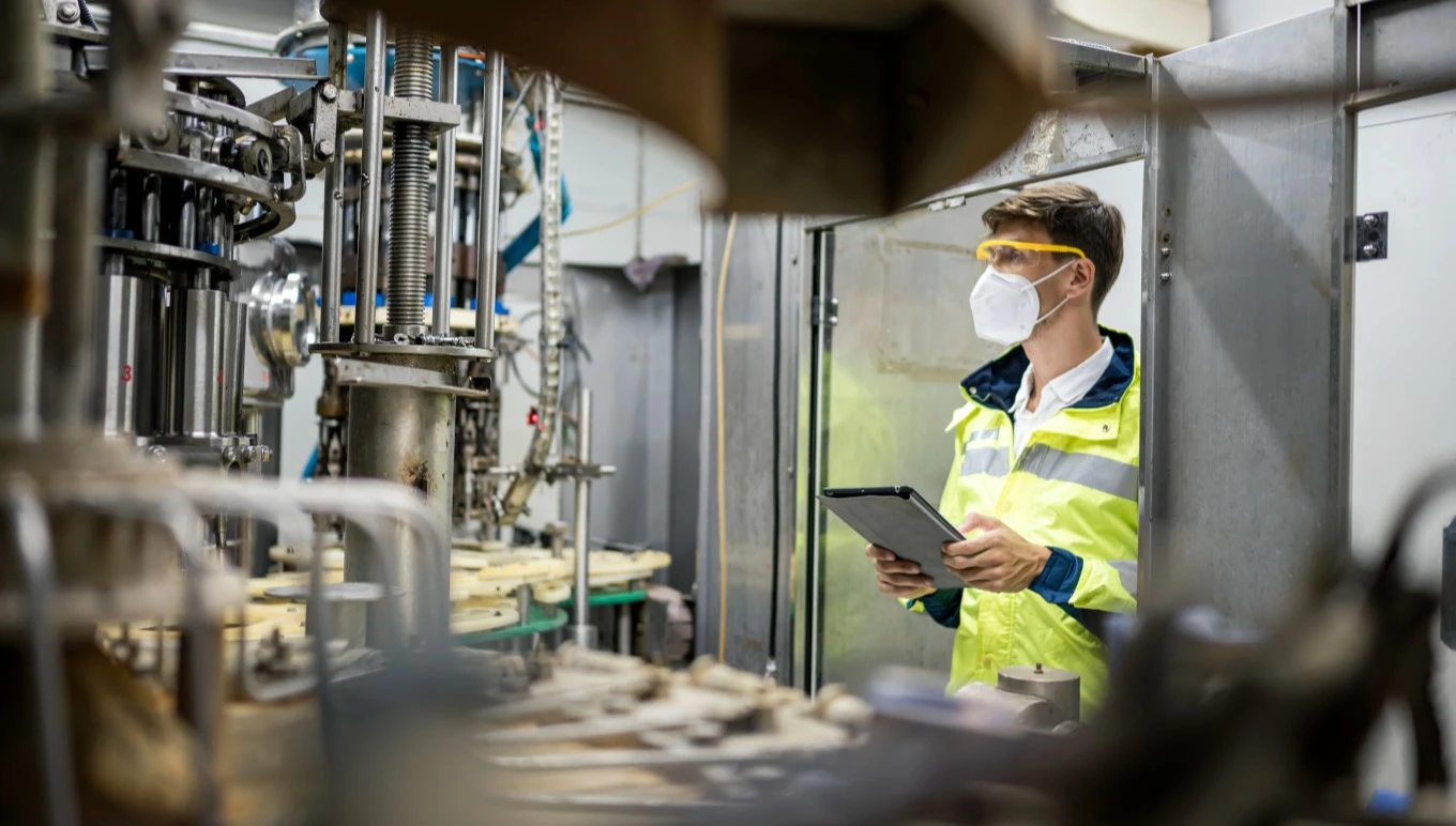 A food facility worker oversees operating machinery.