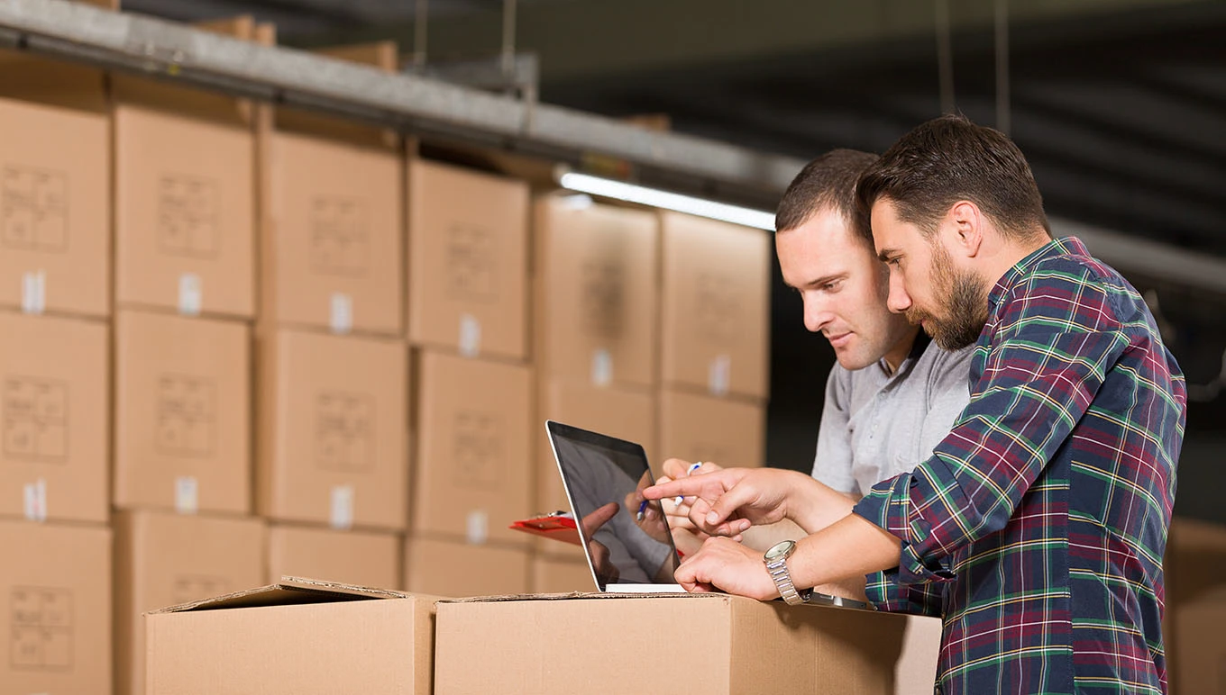 Two people working on a laptop on top of boxes