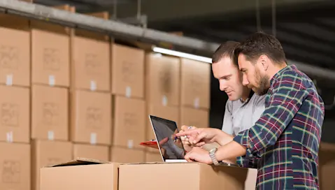 Two people working on a laptop on top of boxes